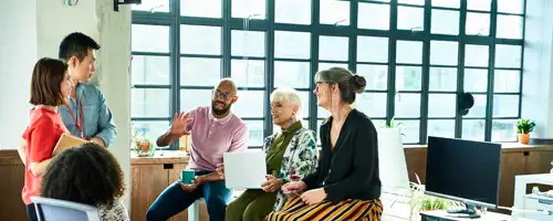 Six people sitting around a desk talking